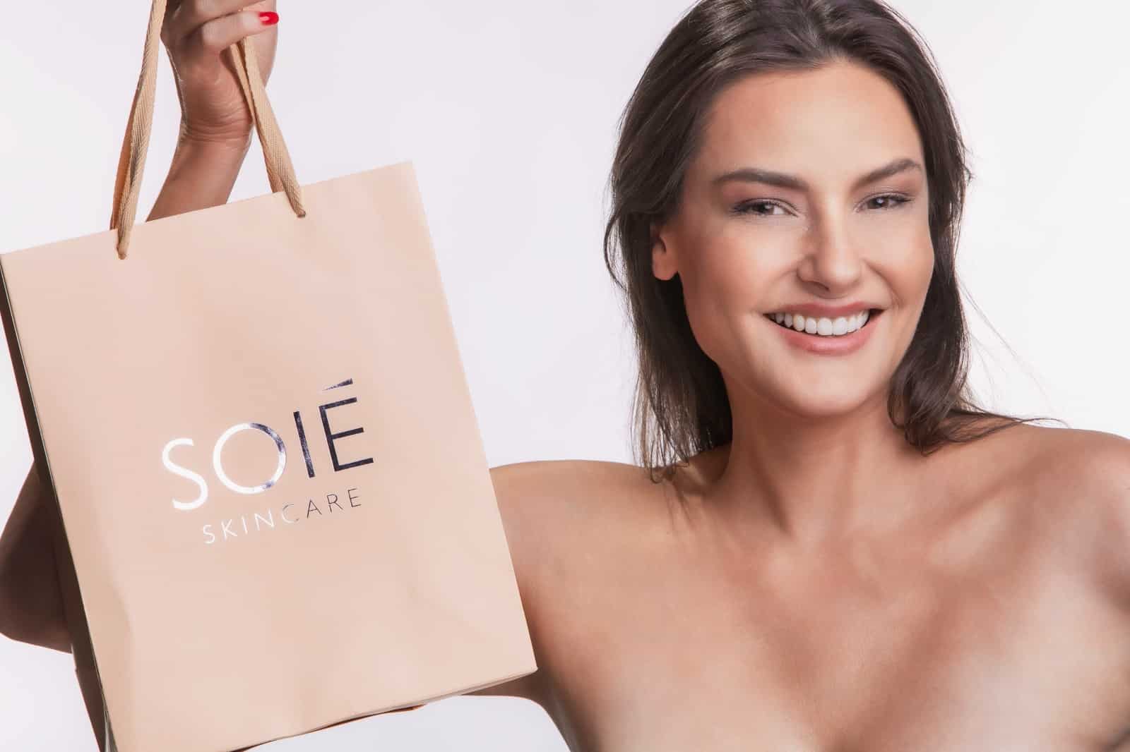 Mulher segurando uma embalagem de produtos da Soié Skincare.
